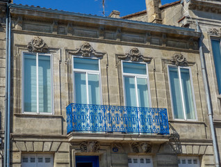 Details of the ornaments of a typical house in the Bordeaux region and its balcony blue