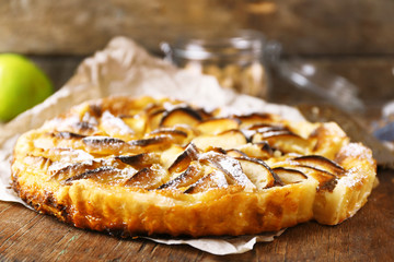 Homemade apple pie on cutting board on wooden background