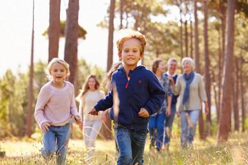 Multi-generation family walking in countryside, kids running