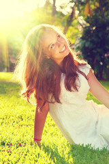 Beauty romantic teenage girl sitting on green grass outdoor