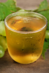 Glass of cool grape juice on wooden table, closeup