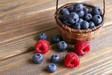 Tasty ripe berries in basket on wooden table close up