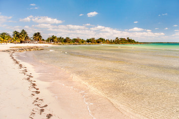 Сoast of one of the islands of Cuba - sea waves, white sand and palm trees.