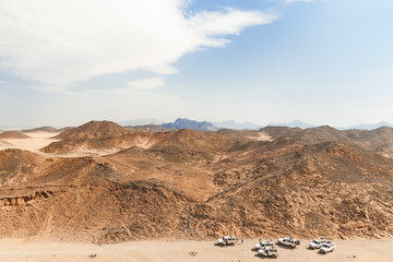 Beautiful desert landscape of Egypt. Safari cars go on the road.