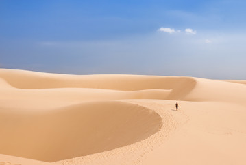 Fototapeta na wymiar Alone man in desert. The White Dunes (bau sen, bau trang)- landmark near Mui Ne, Binh Thuan, Vietnam.