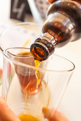 pouring beer from bottle into mug glass