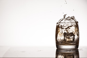 Ice splash into whiskey or brandy