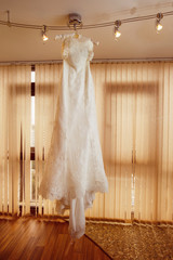 Beautiful luxury white wedding dress is hanging on lustre 