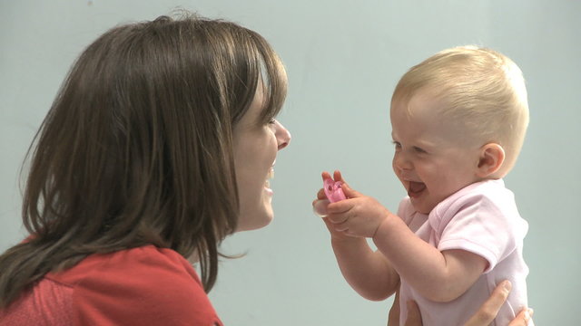 mother and baby daughter playing with a pacifier