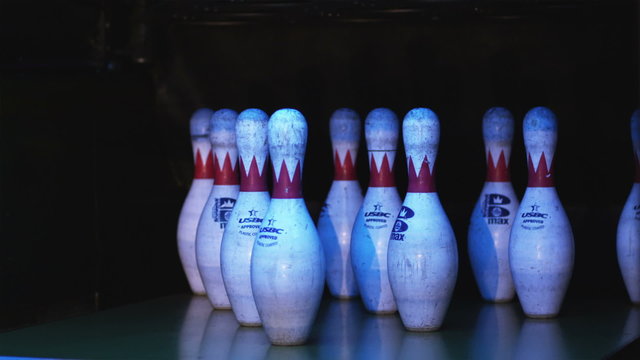 bowling pins being knocked down by a bowling ball in a bowling alley