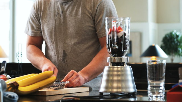 man in the kitchen making a fruit smoothie in the blender