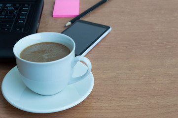 Fototapeta na wymiar Smartphone with coffee and laptop on wooden table and copy spac