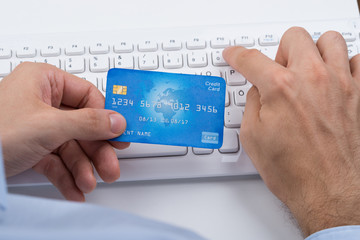 Hands Holding Credit Card On A Keyboard