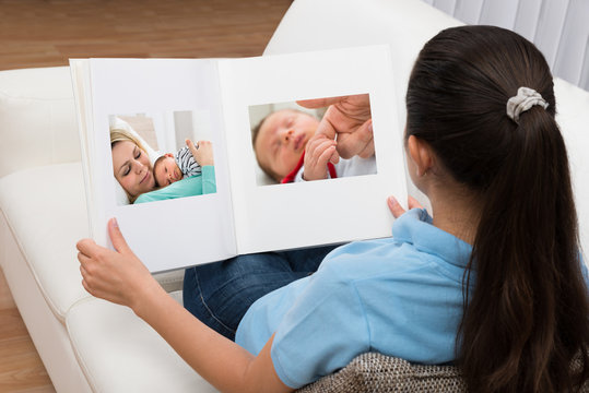 Woman Looking At Photo In Living Room