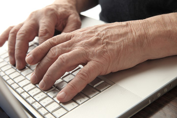 Older man types on his laptop