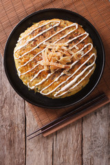 Japanese okonomiyaki on a wooden table. vertical top view
