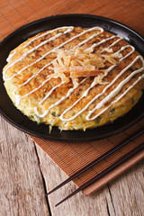 Japanese okonomiyaki on a table close-up and chopsticks. vertical
