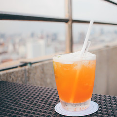 Cocktail glass in rooftop bar against city view