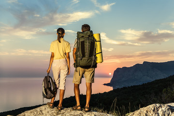 Couple with backpack looking at sunrise