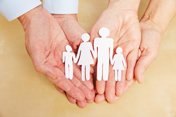 Alte Hände halten Familie aus Papier