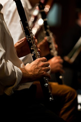 Hands of man playing the clarinet in the orchestra in dark colors 
