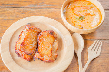 Chicken steak and spicy soup on wooden table