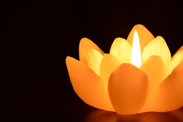 Lit flower candle isolated on black background
