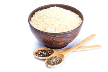 Rice in a bowl of ceramic and wooden spoons with spices.