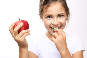 
Zdrowe i mocne zęby dziecka. Dziewczynka w aparacie ortodontycznym z jabłkiem 