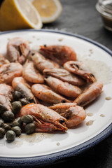 Grilled shrimps with capers on the ceramic plate