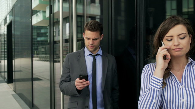 Businesspeople standing next to each other and using smartphones, steadycam shot
