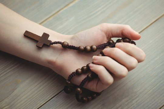 Woman holding wooden rosary beads 