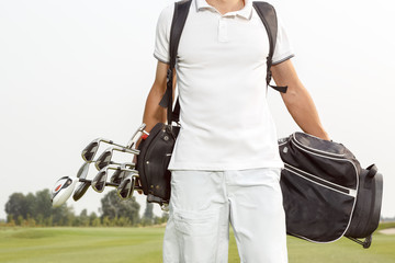 Man carrying his golf bag across course
