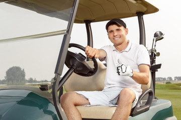 Young man driving cart on a golf course