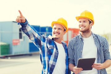smiling builders in hardhats with tablet pc