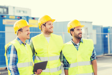 smiling builders in hardhats with tablet pc