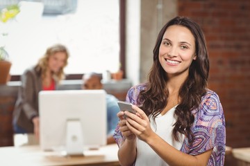 Smiling businesswoman using smartphone in office