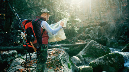 Walking hiker looking at map. Hiking in beautiful autumn forest.