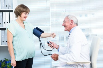 Obraz premium Doctor checking blood pressure of pregnant woman
