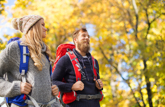 smiling couple with backpacks hiking over autumn