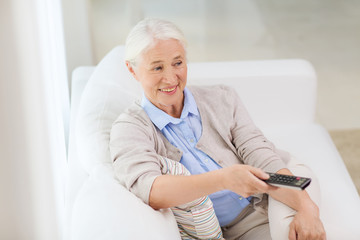 happy senior woman watching tv at home