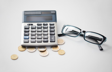 calculator, glasses and euro coins on office table