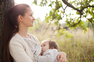 young mother feeding toddler outdoors