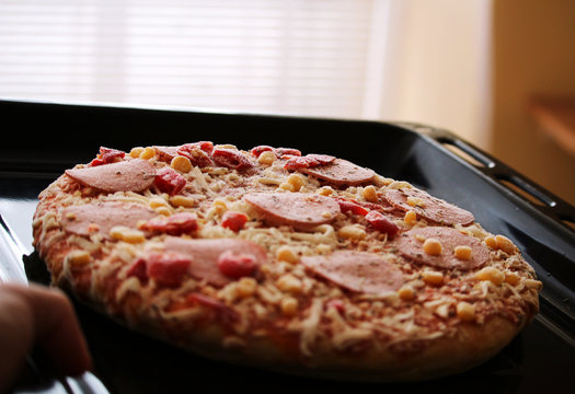Frozen pizza with salami, cheese, corn and pepper