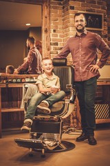 Stylish little boy and his father in a barber shop