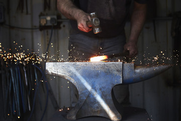 Blacksmith shaping piece of iron in workshop