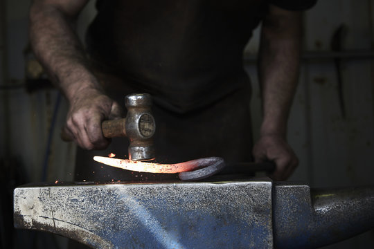 Blacksmith shaping piece of iron in workshop