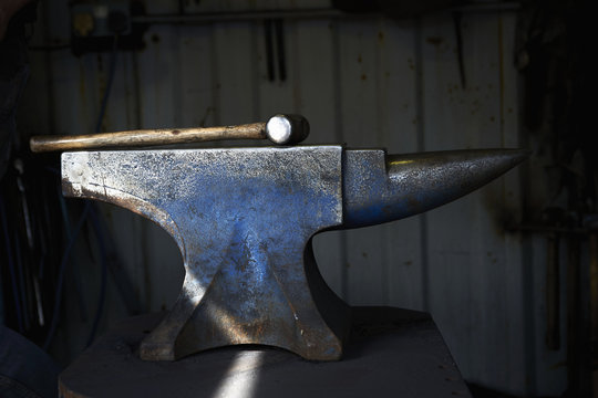 Hammer lying on an iron anvil in a traditional blacksmith's forge.