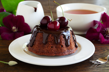 Chocolate cake with icing and a cherry.