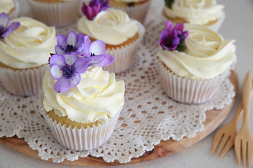 Edible purple freesia flowers on vanilla cupcakes with whipped c